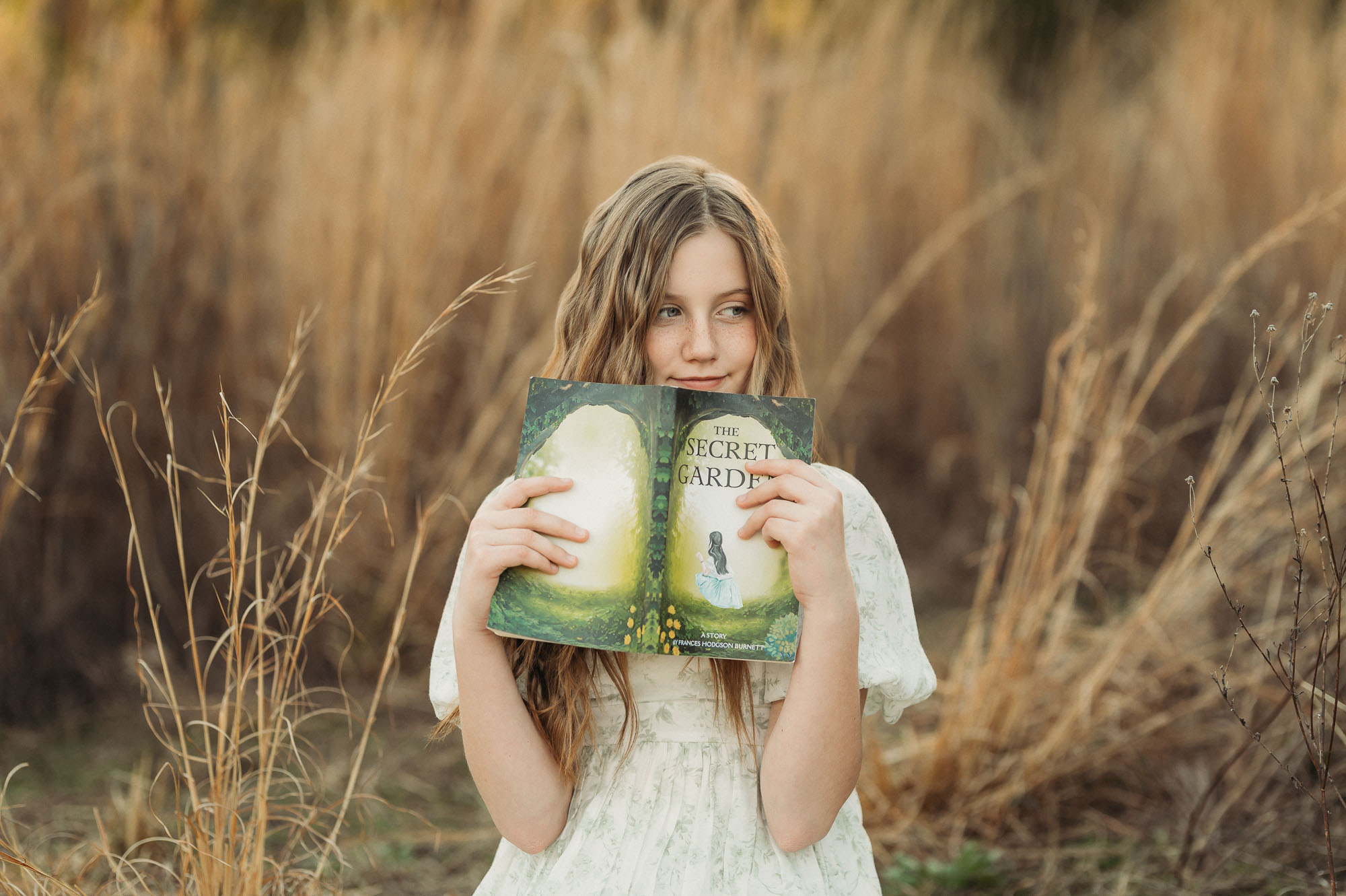 Girl reading book in meadow with dry grass | East Texas Child Photographer 