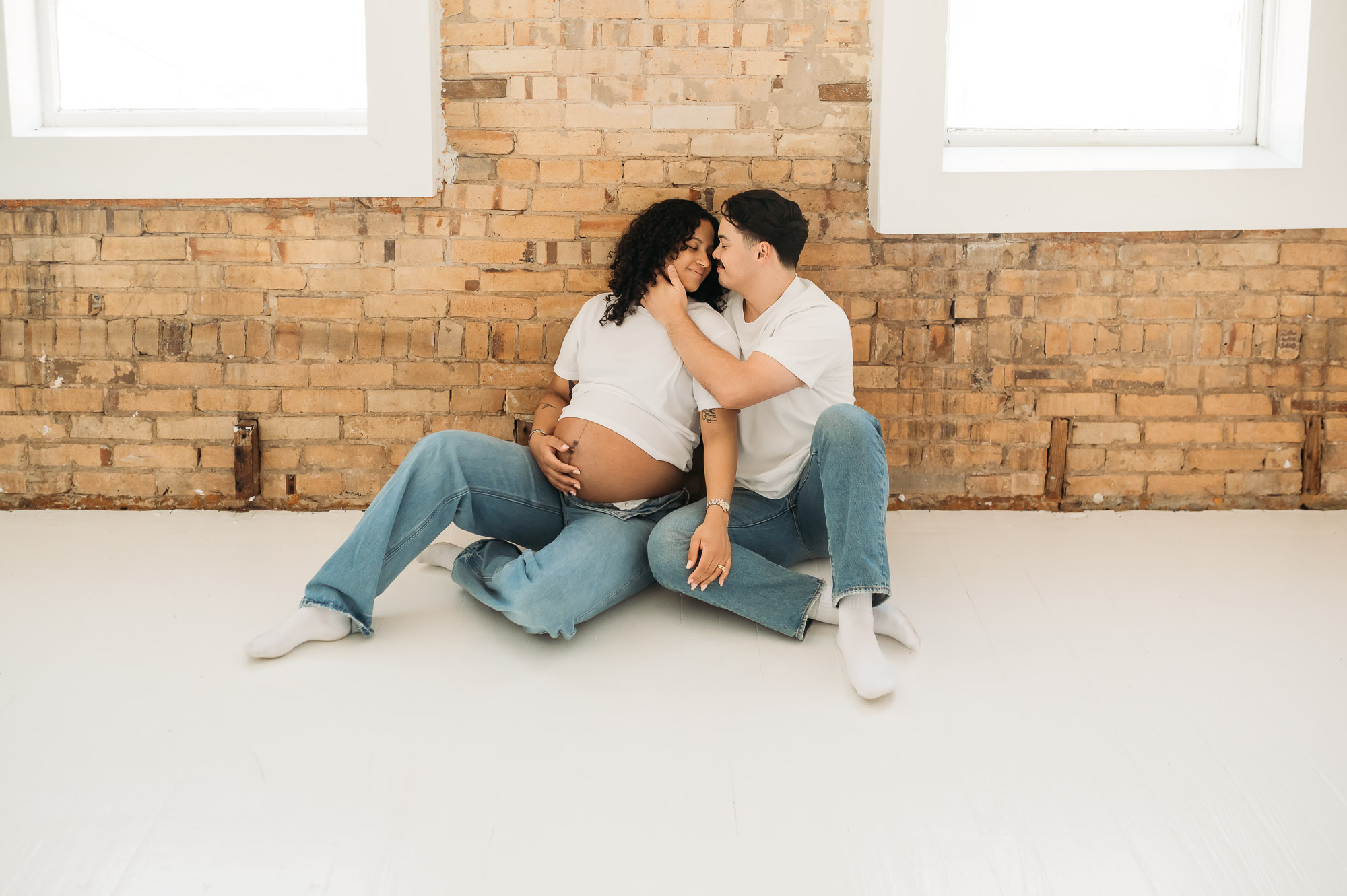 An expecting mom and dad posing in front of a studio window | Lindale Texas Maternity Photographer 