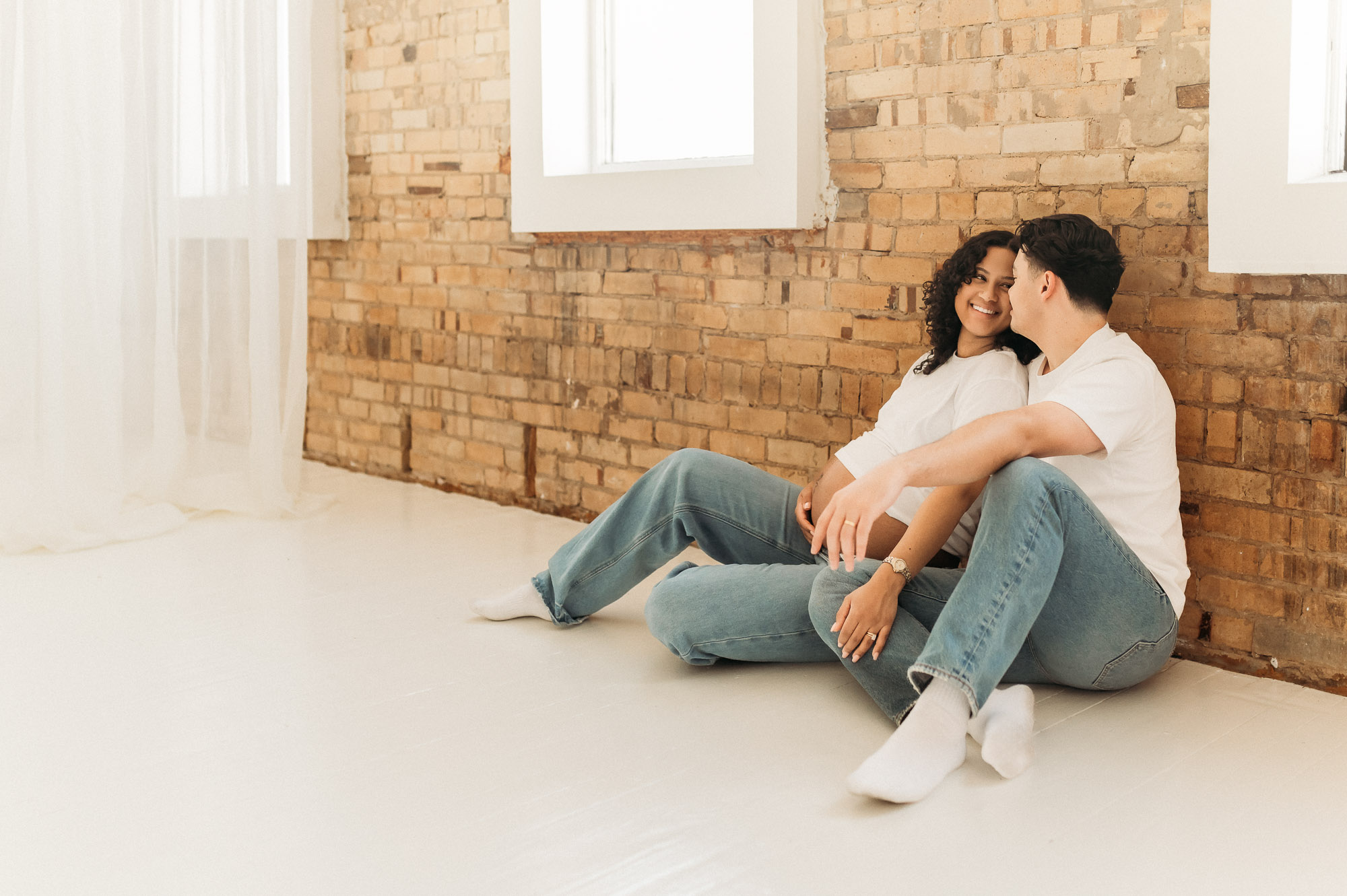 An expecting mom and dad posing in front of a studio window | Lindale Texas Maternity Photographer 