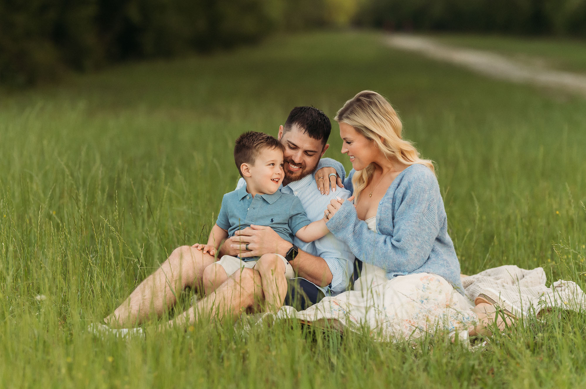 Family snuggling in long grassy meadow | Lake Tyler Family Photography