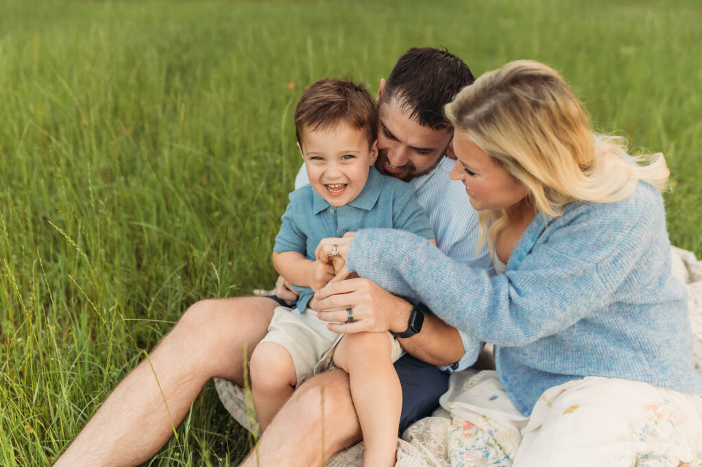 Family snuggling in long grassy meadow | Lake Tyler Family Photography