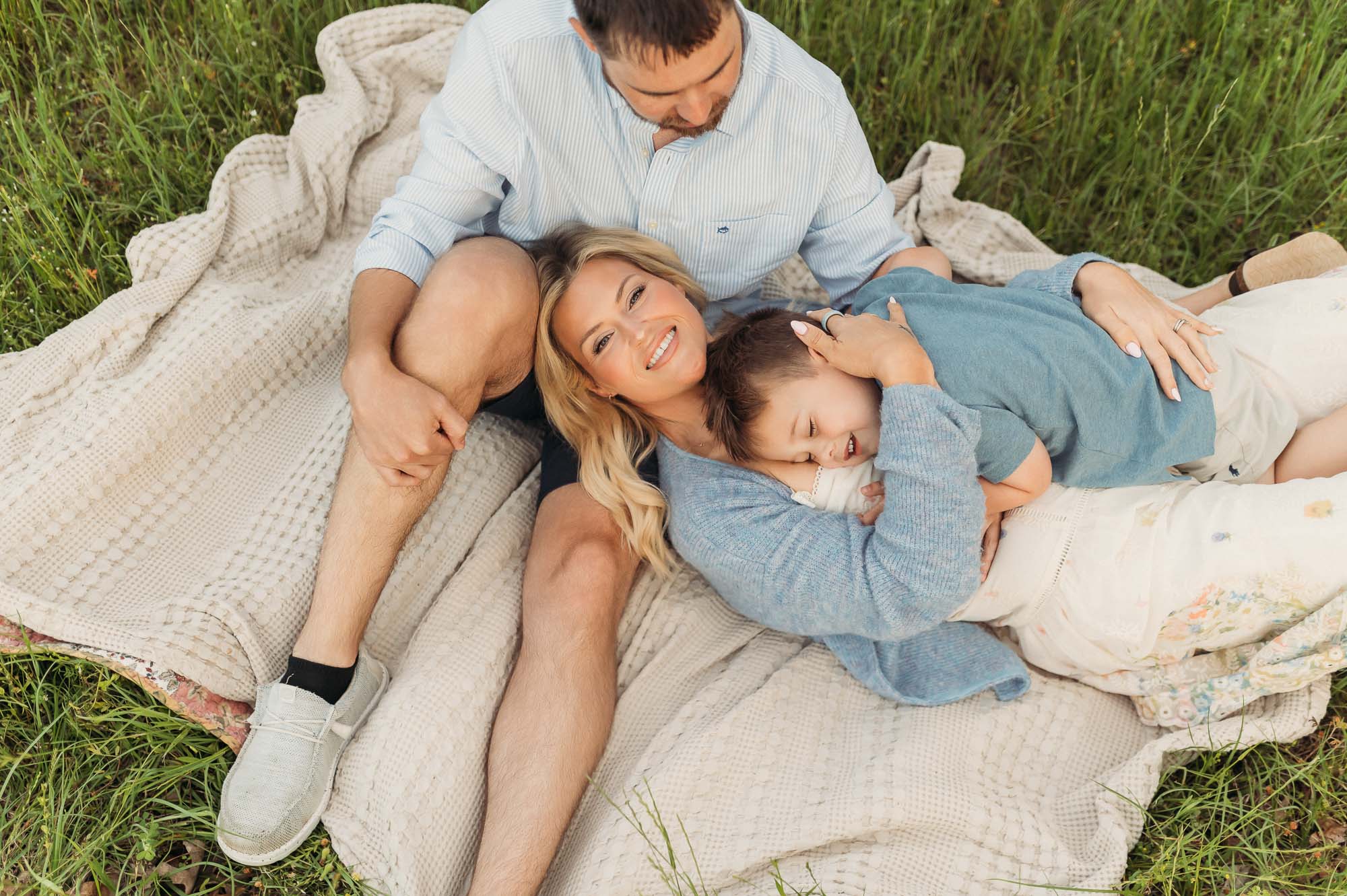 Family snuggling in long grassy meadow | Lake Tyler Family Photography