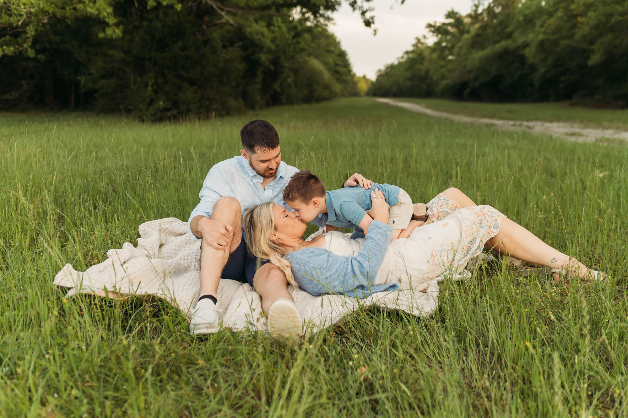 Family snuggling in long grassy meadow | Lake Tyler Family Photography
