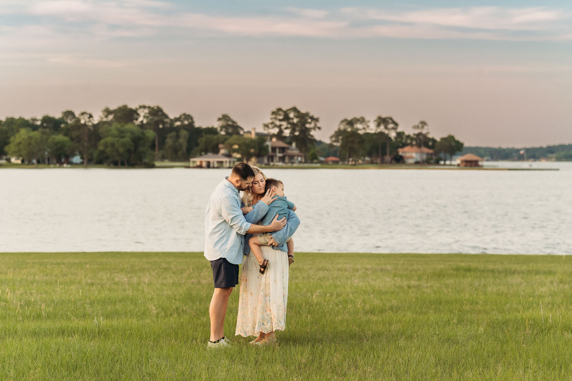 Family snuggling in grass by the lake | Lake Tyler Family Photography