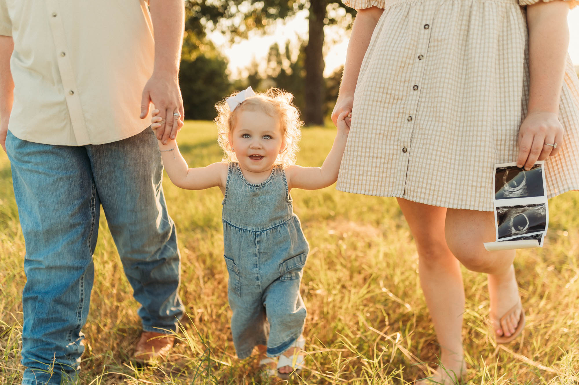 Family walking in a grassy meadow | East Texas Pregnancy Photographer