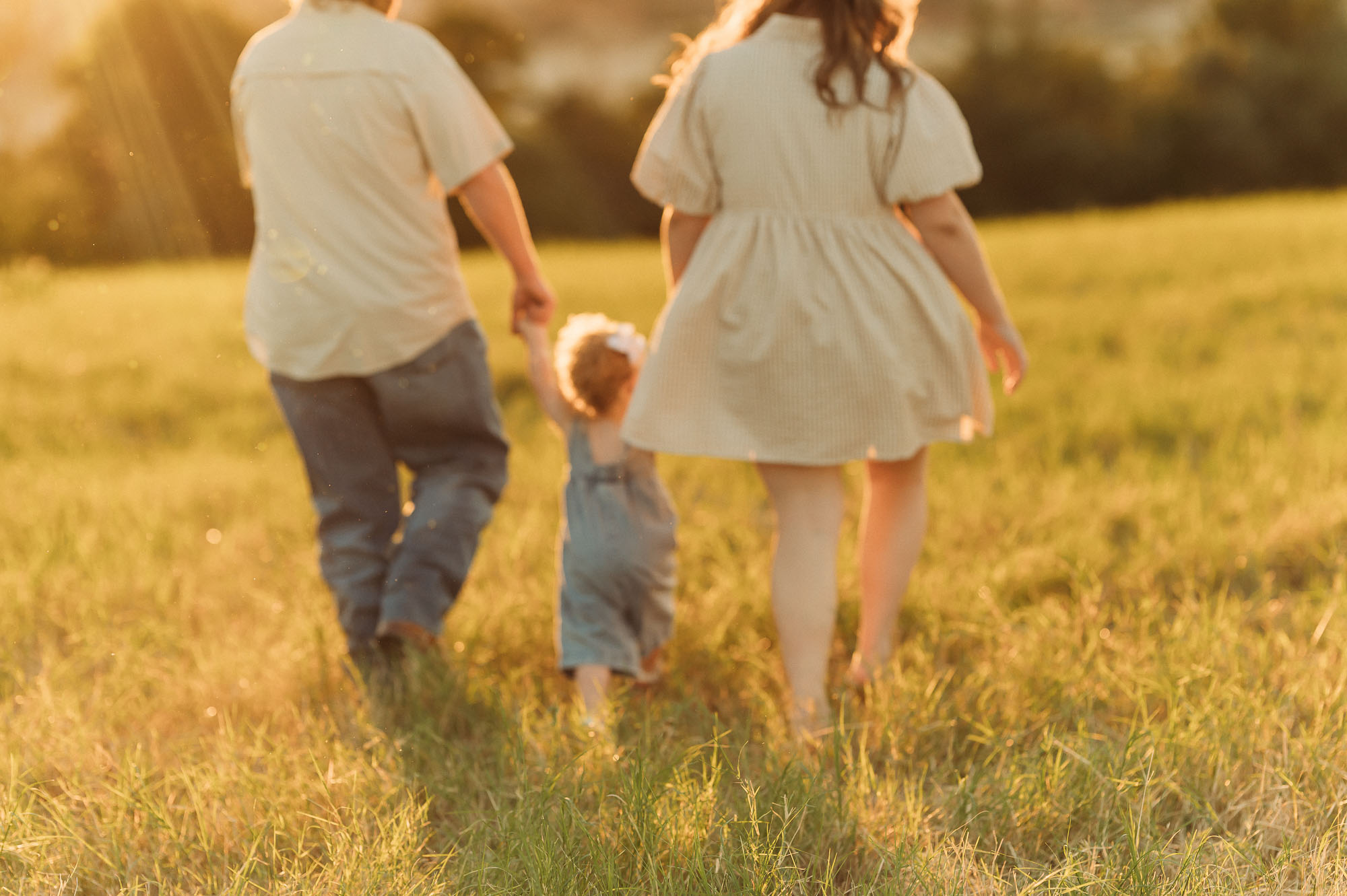 Family walking in a grassy meadow | East Texas Pregnancy Photographer