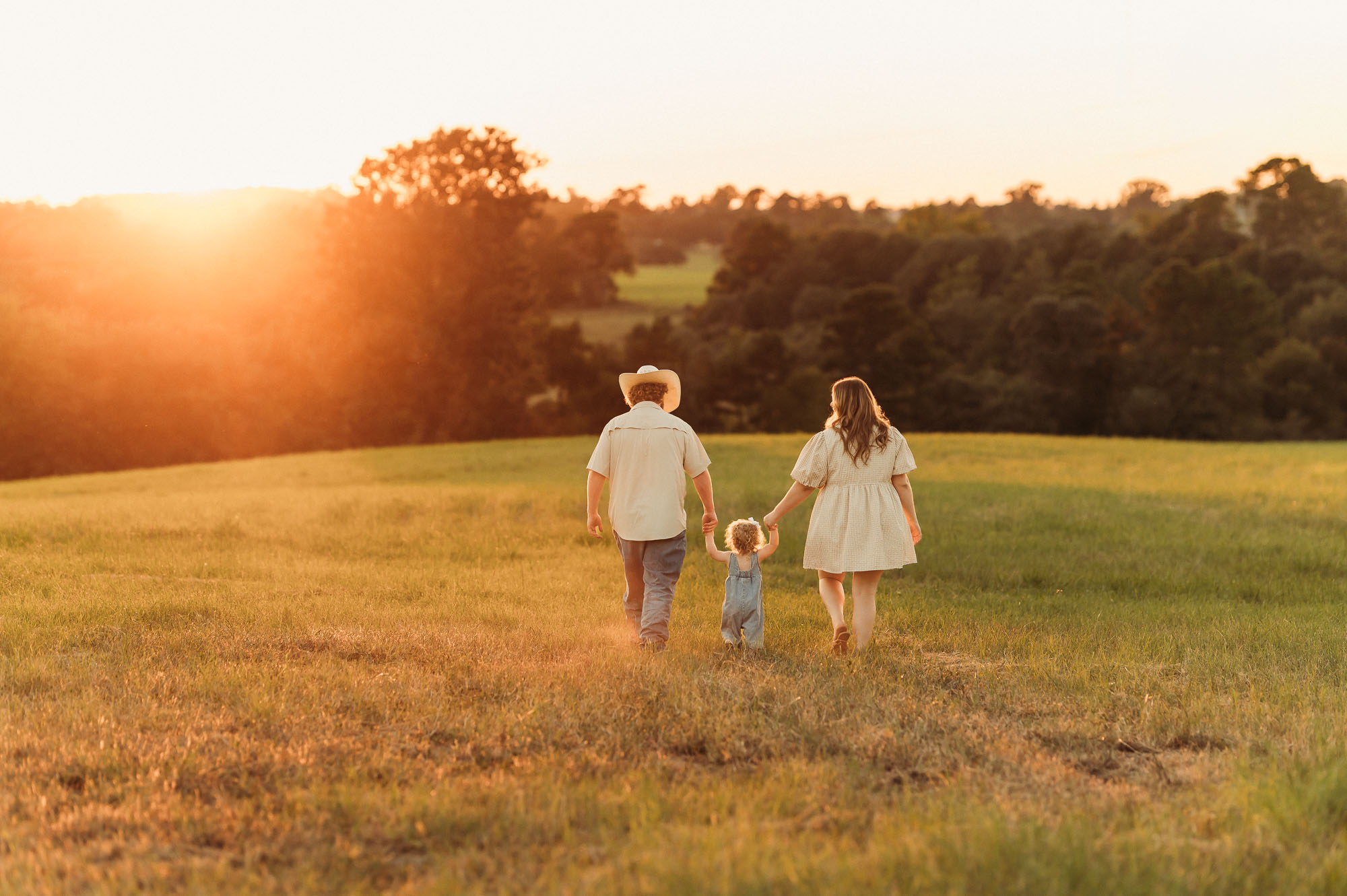 Family walking in a grassy meadow | East Texas Pregnancy Photographer